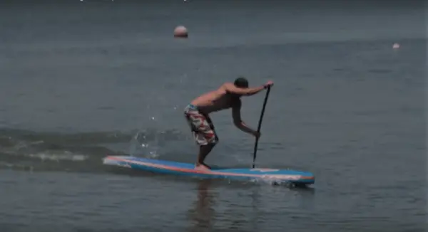 get low to minimize wind resistance when paddle boarding in strong winds